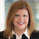 Woman in headshot wearing black jacket with white button up shirt underneath