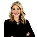 Woman smiling with curled blonde hair. She is wearing a black shirt.