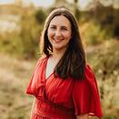 Betsy wearing a red dress in front of a field