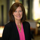 Head shot of Christina in a pink shirt and black blazer in front of blurred background