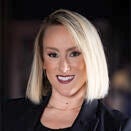 Woman with shoulder length blond hair, wearing black jacket and black top