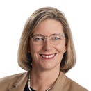 Woman with shoulder length brown hair, wearing brown jacket and black top