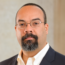 Enrique Duarte Melo smiling with mouth closed and wearing a white shirt with black suit jacket