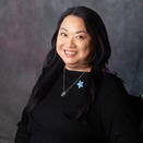 Headshot of Lillian in a black shirt with a blue star pin