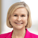 Joan Holman smiling and wearing a pink blazer