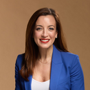 Kim Elenez smiling and wearing a white shirt with blue blazer