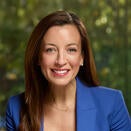 Kim Elenez smiling and wearing a white shirt with blue blazer