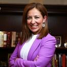 Marissa Solis smiling and wearing a white blouse with purple blazer