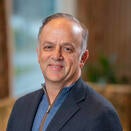 A man with short hair, wearing a blue jacket with light blue shirt.