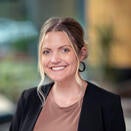 Woman with blond hair, dark jacket brown top