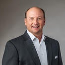 Russ Webb smiling and wearing a white shirt with grey suit jacket