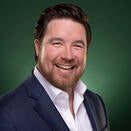 Ryan Chismark smiling and wearing a white shirt with navy suit jacket