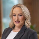 Woman with shoulder length blond hair, wearing black jacket and white top