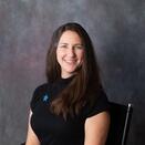 Headshot of Betsy in a black shirt with a blue star pin