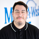 Bryan Ortiz, Senior Wish Manager, in front of Wish Wall