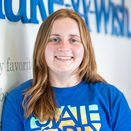 Lauren Kuhman, Donor Care Manager, standing in front of Wish Wall