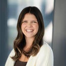 Woman with brown shoulder length hair with white sweater and brown top