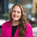 woman with long brown hair, pink jacket and black top