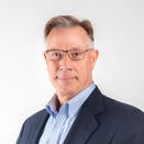 A man with glasses giving a soft smile looking at the camera