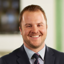 A man in a suit smiling in his office.