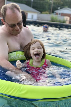 Anna laughing as she plays in her new pool with her dad