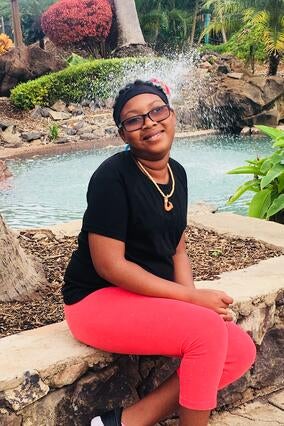 Malayna sitting and smiling by a pond.