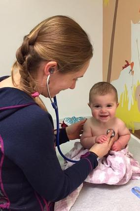 Dr. Carlson examines a smiling baby on a scale in a doctor's office