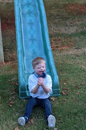 Gavin's wish to have an adaptive playset, smiling on slide