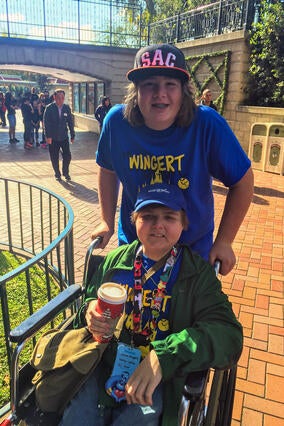 Jacob pushing his brother Joshua around during his wish trip to Disneyland® Resort