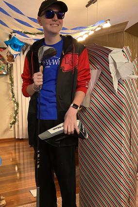 Elijah poses with his gifts from his online shopping spree, including new golf clubs.