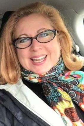 Jane smiling with red hair, glasses, and scarf