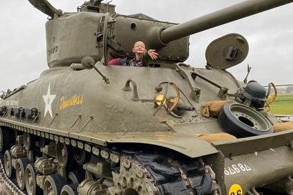 Six-year-old wish kid Korbyn waves outside an opening of a World War II Sherman tank.