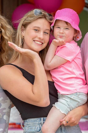 Reese holding Izzy while the two blow kisses to the camera
