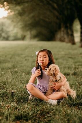 Maelin-Kate blowing on a dandelion, holding her new puppy