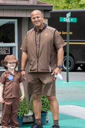 JoJo in his brown UPS uniform with his trainer, Paulo, at the UPS Integrad driver training facility.