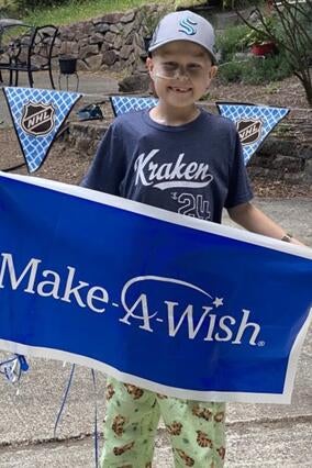 Jackson during his wish reveal holding a make-a-wish banner.