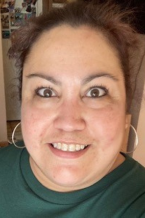 Christina smiles for camera, close up hair pulled back. 