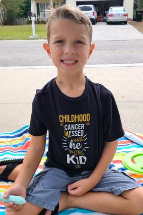 Rowan seated outside wearing a cancer warrior tshirt