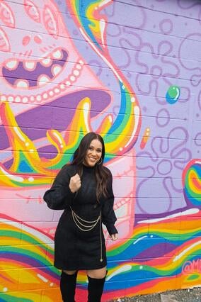 Serena in front of a colorful painted mural wall