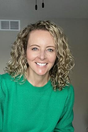 Nicole Becker smiling in a green sweater with a plain background