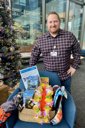 Derek standing with gifts in front of a Christmas tree