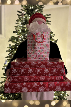 Wish kid Emma holding a tour of wrapped gifts in front of her Christmas tree