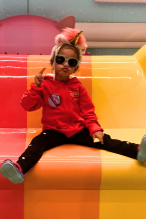 Xyla on rainbow bench wearing a unicorn horn