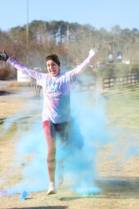 A woman crosses the finish line of the 5th-annual Running Outside the Lines color run.