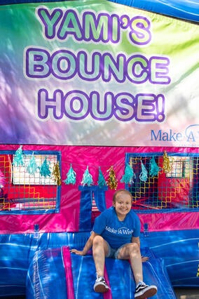 Wish kid Yami sitting in front of a bounce house