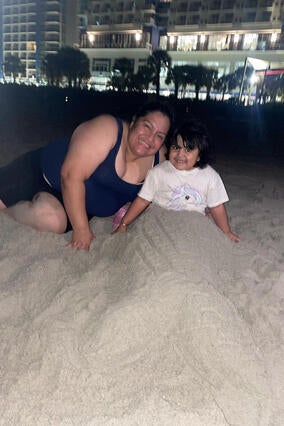 Wish kid Gigi in the sand with her mom