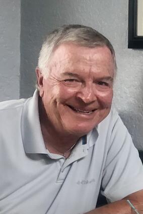 Wayne in a grey pullover smiling at the camera