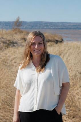 MJ in a white shirt and black pants posing for the camera at the beach