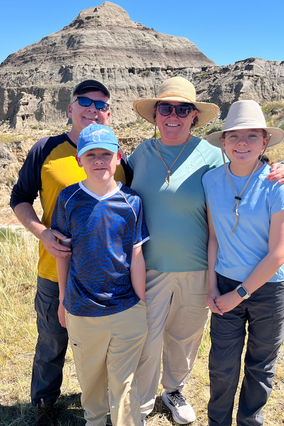 Ian and his family with the Badlands of South Dakota in the background, on his dino dig