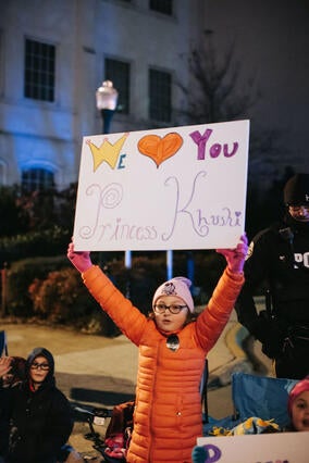 Khushi's classmate holding a sign that reads "we love you Princess Khushi"